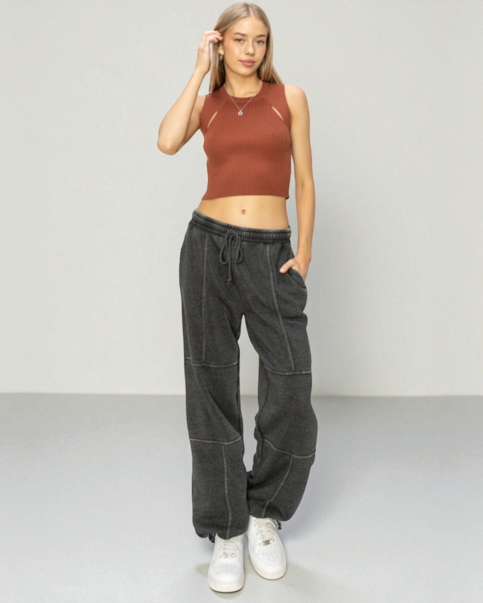 Woman wearing a brown crop top and black high-waisted pants on a plain background
