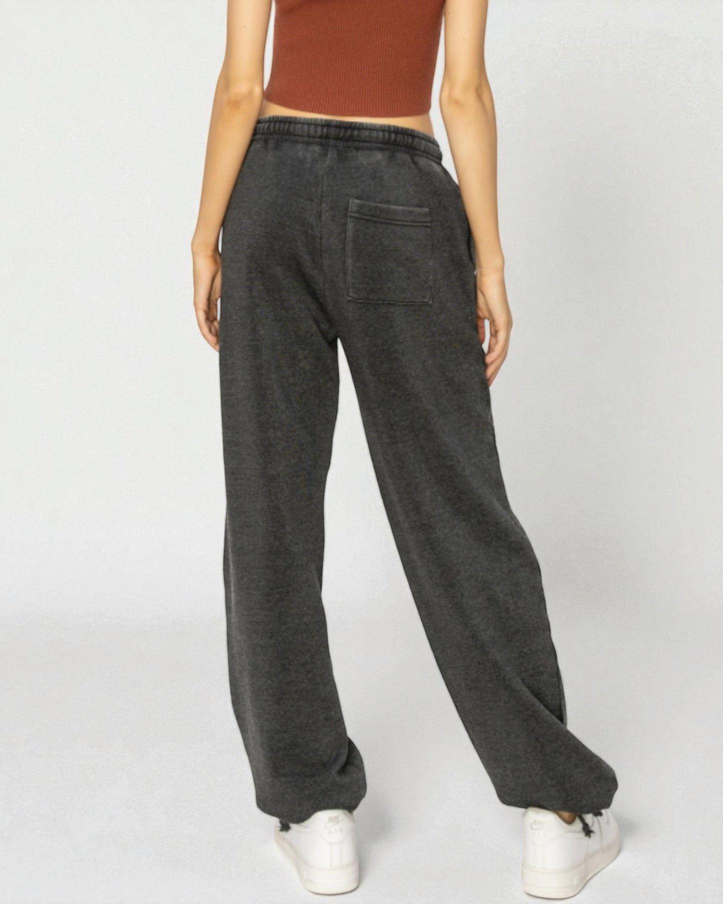 Person wearing dark gray sweatpants on a white background