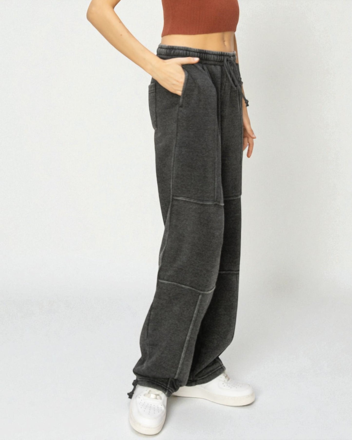 Person wearing dark gray wide-leg pants with a plain background