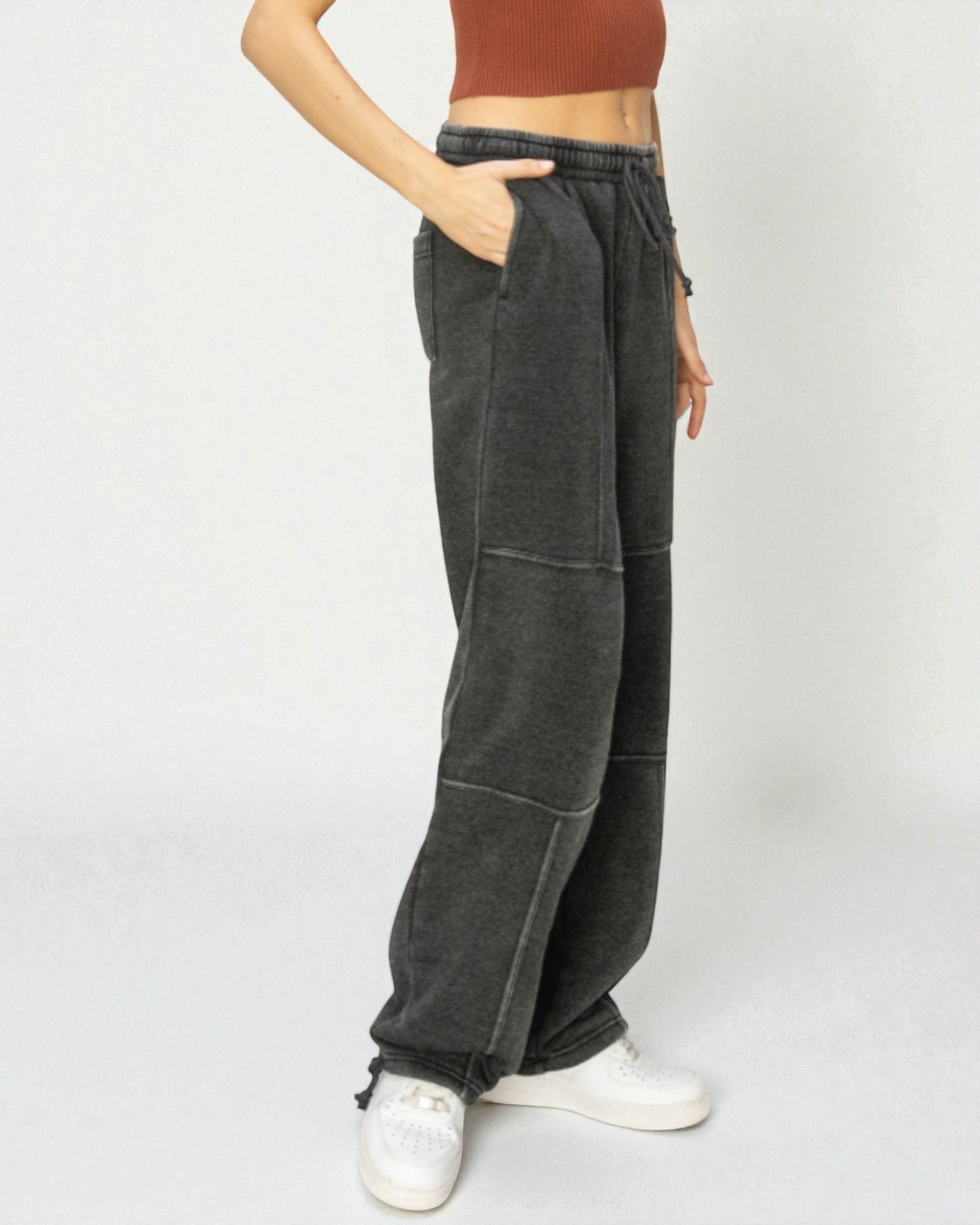 Person wearing dark gray wide-leg pants with a plain background