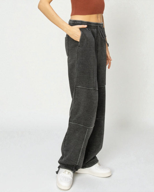 Person wearing dark gray wide-leg pants with a plain background