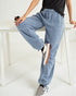 Person wearing light blue jogger pants sitting on a white bench.