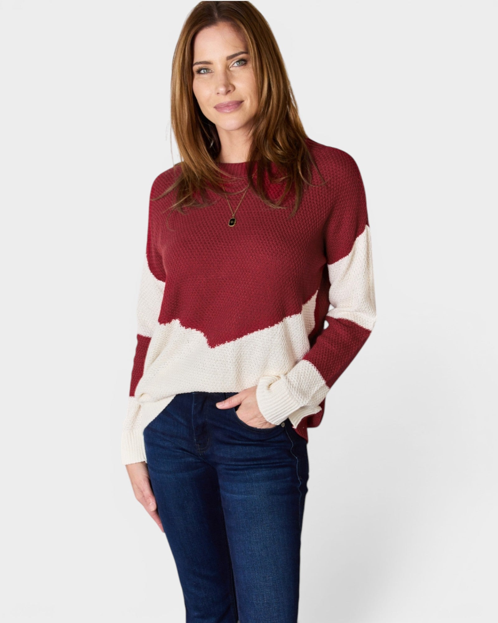 Woman wearing a red and white sweater with blue jeans on a white background