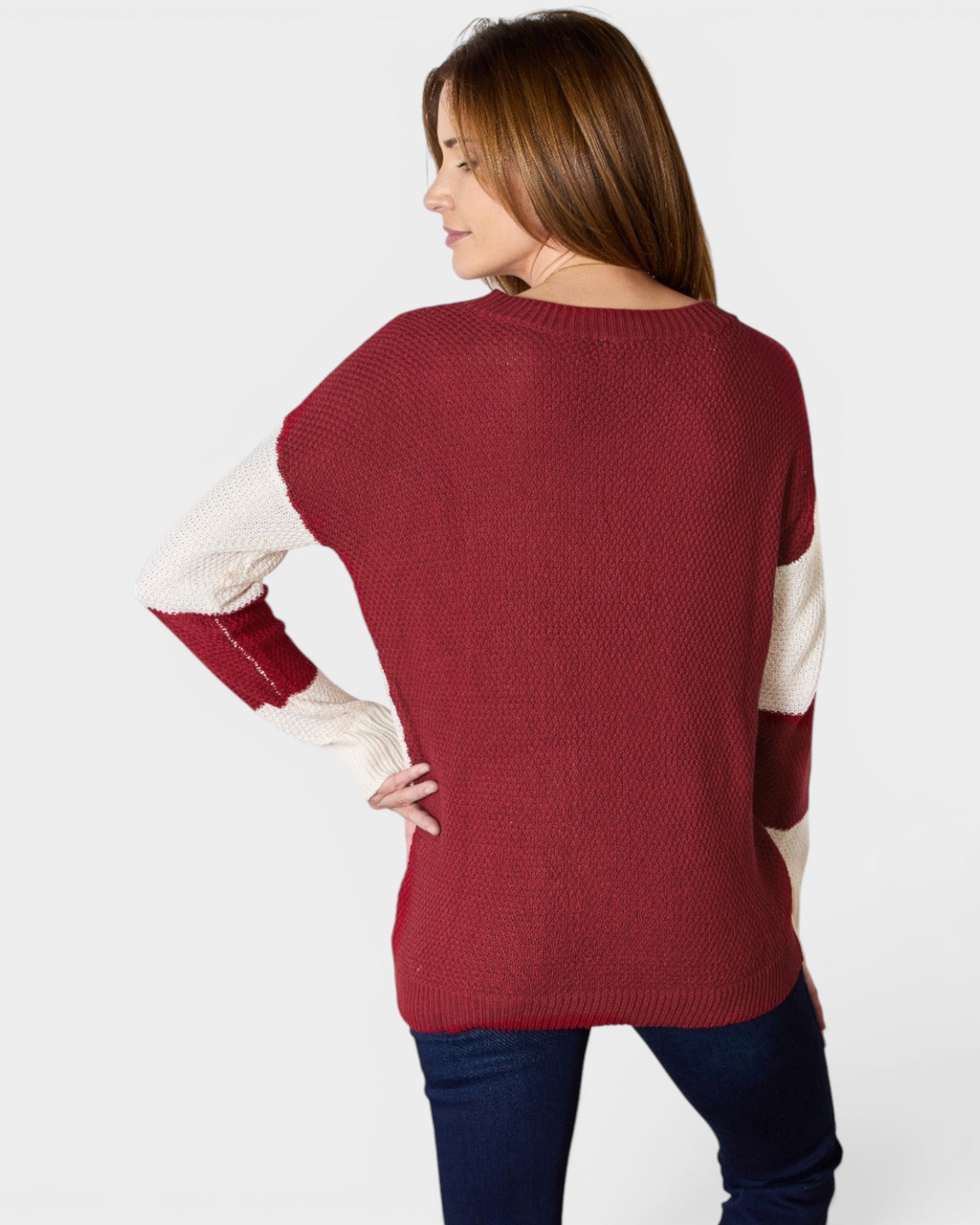 Woman wearing a red sweater with white sleeves on a plain background