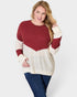 Woman wearing a red and beige sweater with blue jeans on a white background