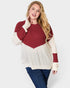Woman wearing a red and beige sweater with blue jeans on a white background
