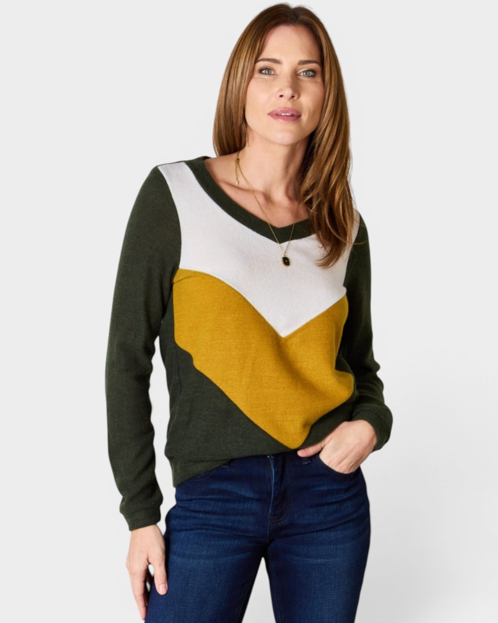 Woman wearing a color-blocked sweater with green, white, and mustard yellow sections on a plain background.