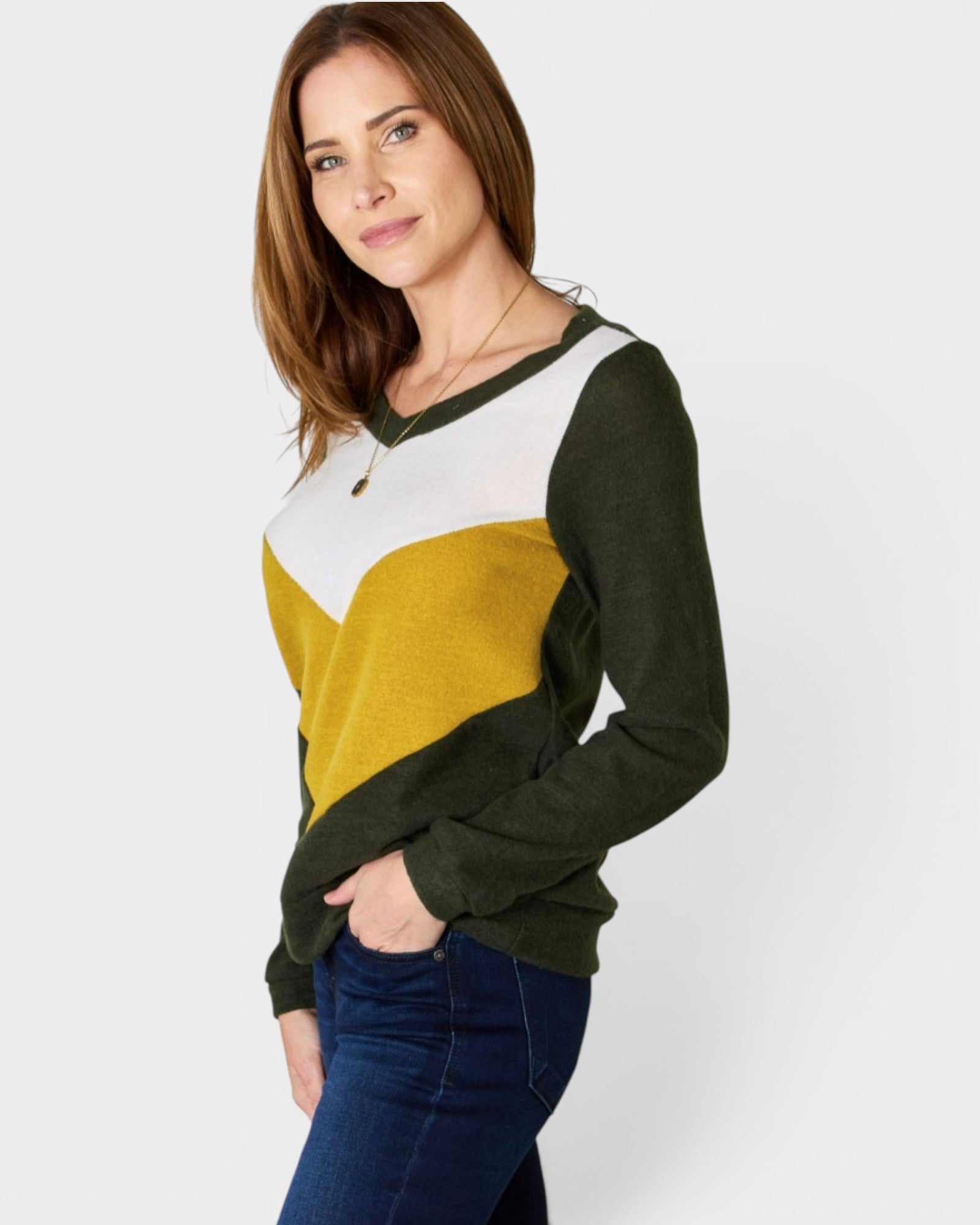 Woman wearing a color-blocked sweater with green, yellow, and white on a plain background