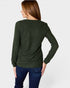 Woman wearing a green sweater and blue jeans on a white background