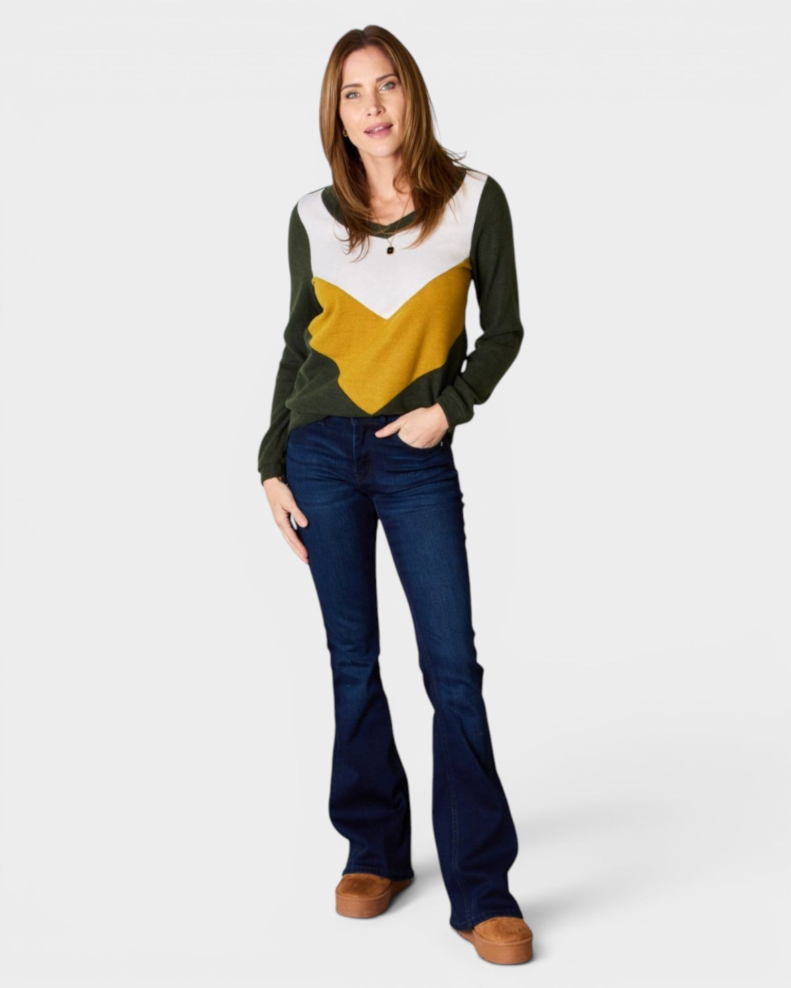 Woman wearing a color-blocked sweater and jeans on a white background