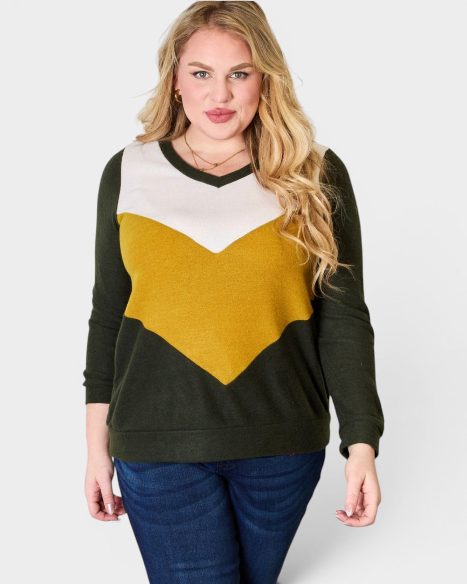 Woman wearing a sweater with a green, white, and yellow color block design on a plain background