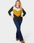 Woman wearing a color-blocked sweater and blue jeans on a white background