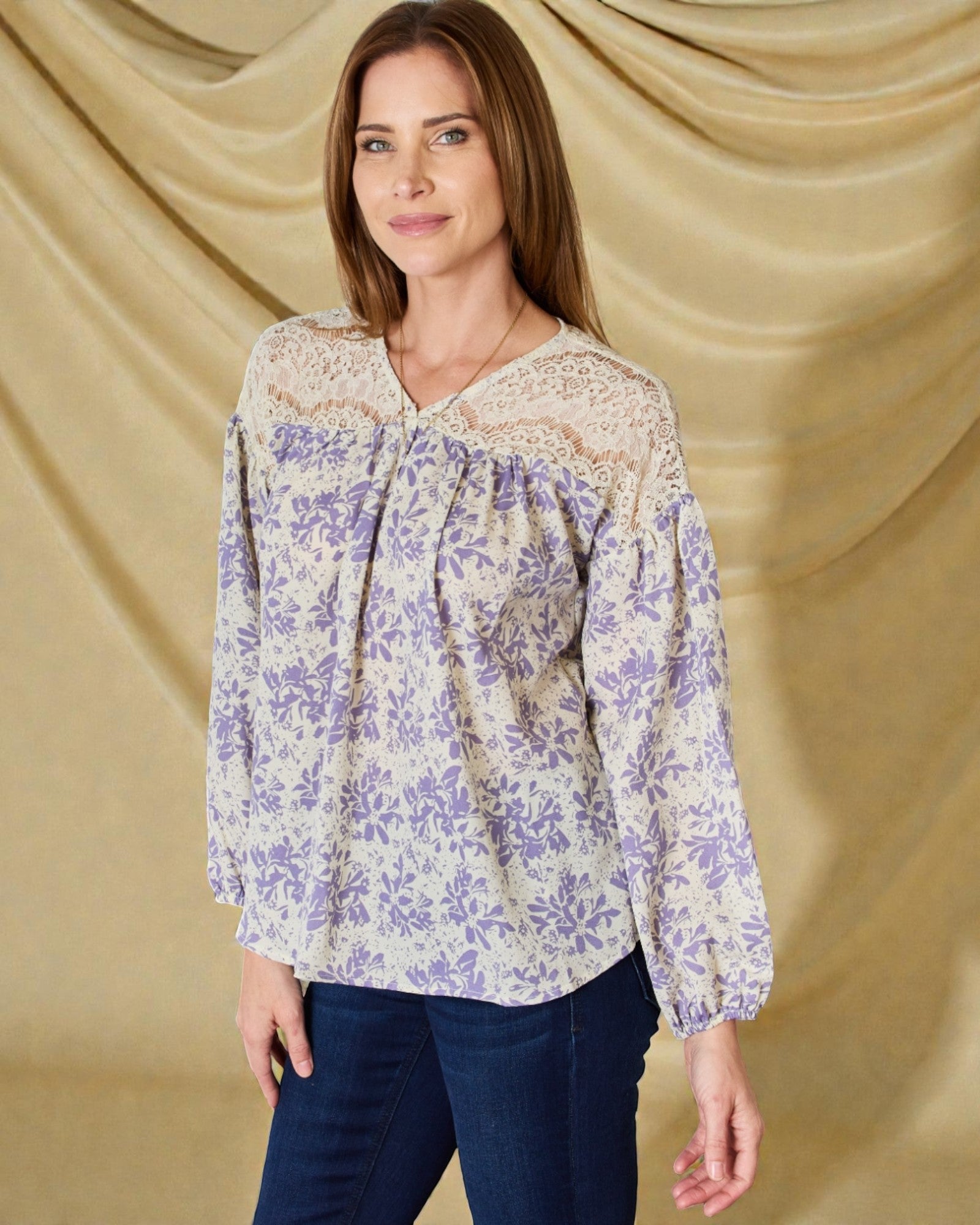 Woman wearing a floral blouse against a beige curtain background