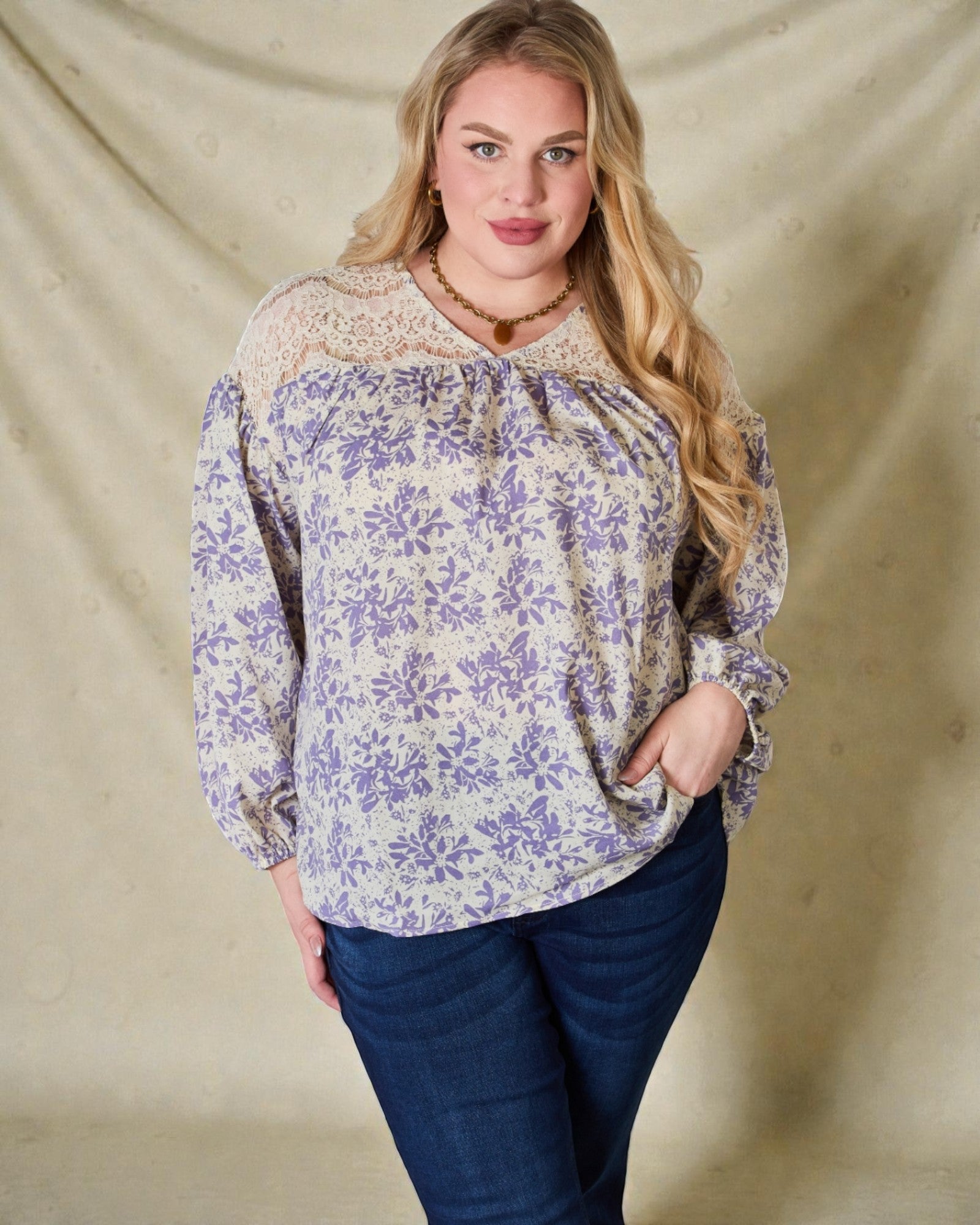 Woman wearing a floral blouse and blue jeans against a beige background
