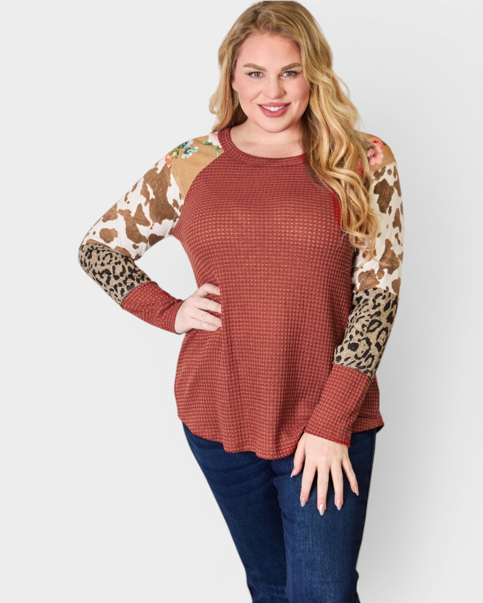 Woman wearing a rust-colored sweater with animal print sleeves on a white background