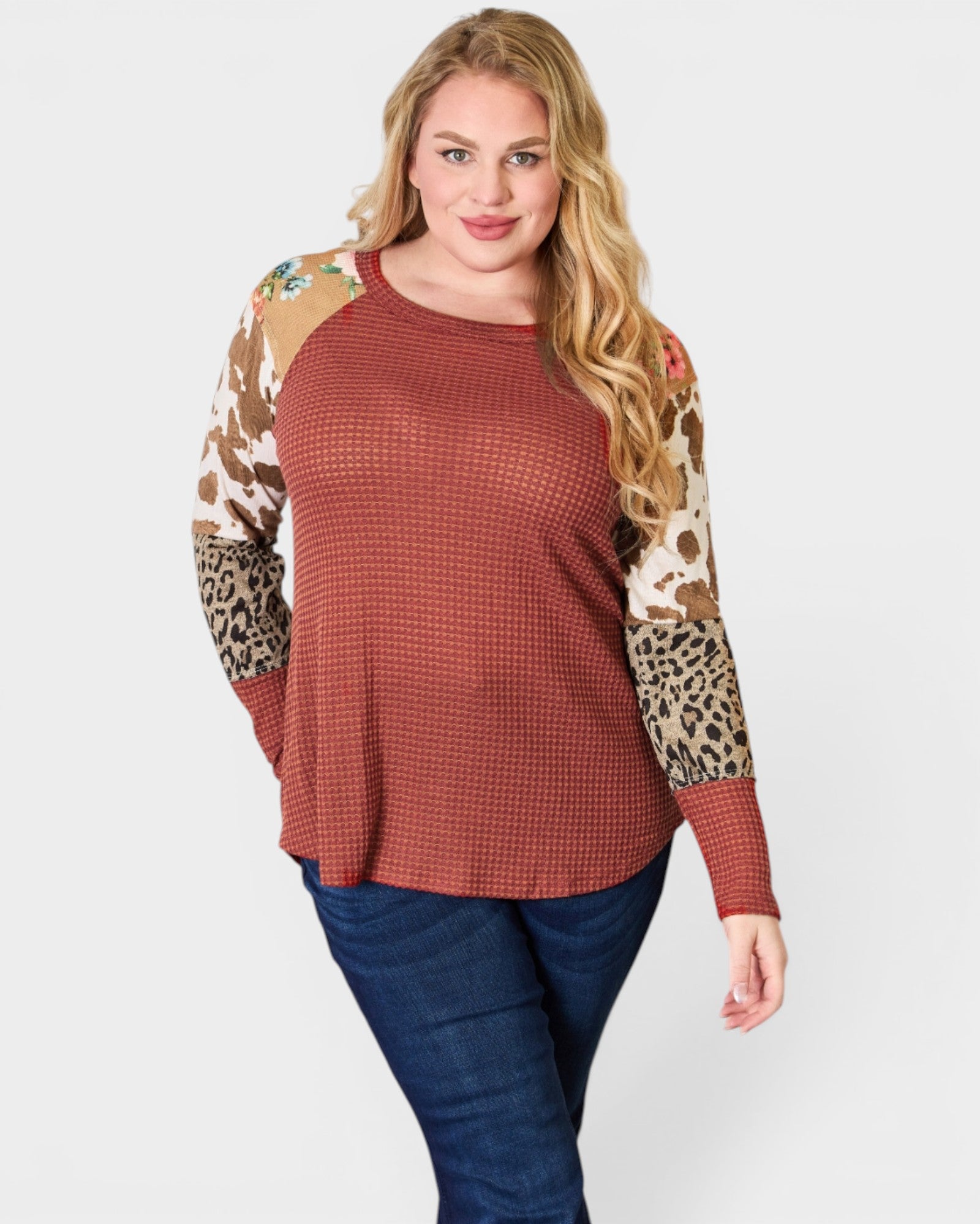 Woman wearing a brown waffle knit top with leopard print sleeves on a white background