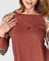 Woman wearing a rust-colored textured top with floral and leopard print sleeves on a white background