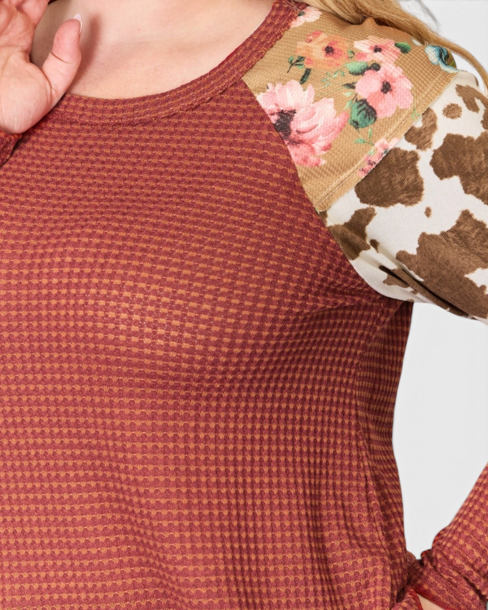 Close-up of a red textured shirt with floral and cow print sleeves.