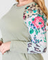 Person wearing a green sweater with floral and leopard print sleeves.
