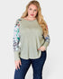 Woman wearing a green sweater with floral sleeves on a white background