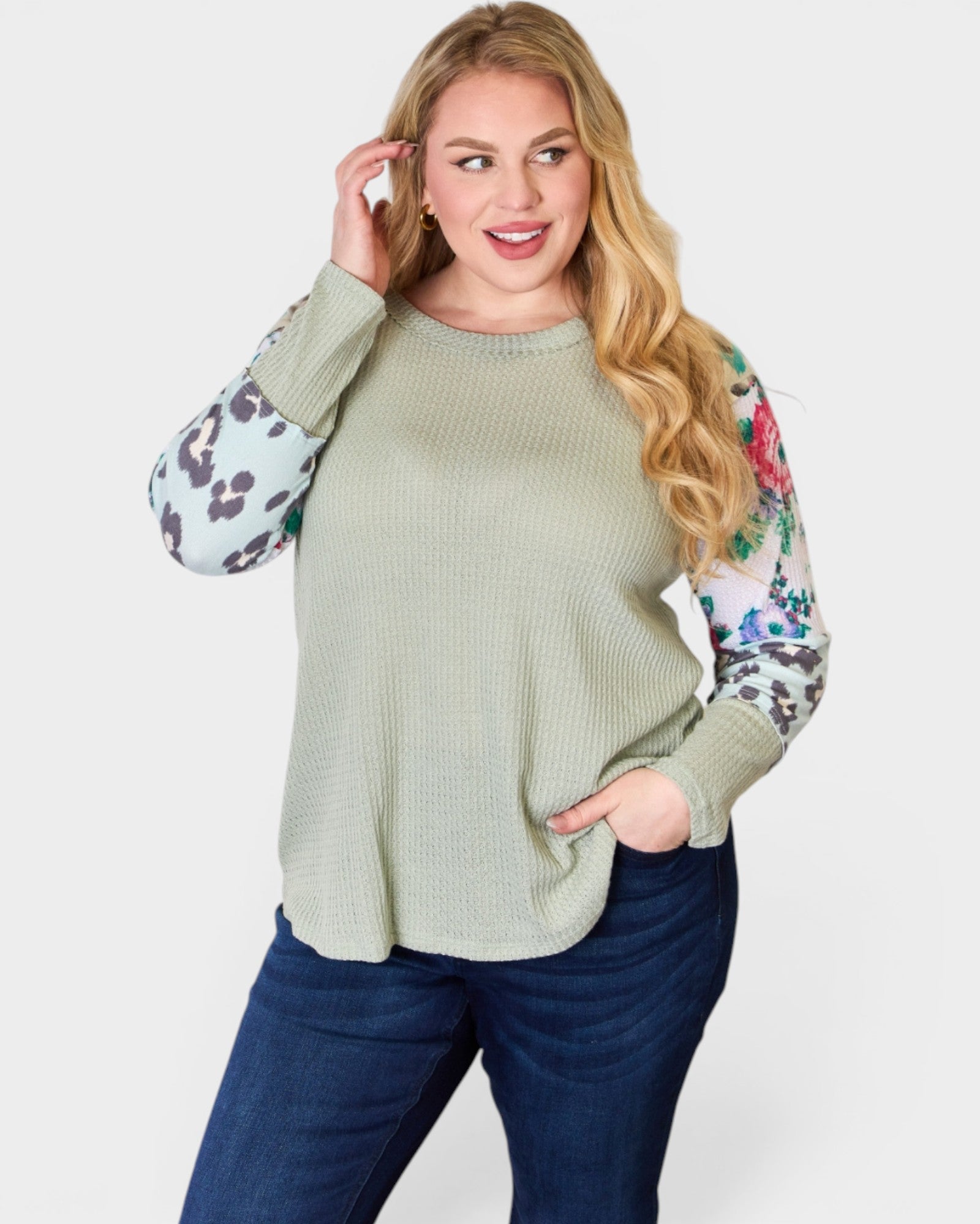 Woman wearing a green sweater with patterned sleeves on a white background