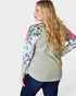 Woman wearing a light green sweater with floral and animal print sleeves on a white background