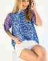 Woman wearing a blue floral blouse and white shorts on a white background