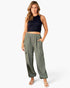 A woman modeling a sleeveless black crop top and olive green wide-leg cargo pants with side pockets, paired with beige strappy sandals, against a plain white studio background.
