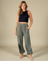 Woman wearing a black sleeveless top and green wide-leg pants on a beige background