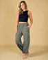 Woman wearing a black sleeveless top and green wide-leg pants on a beige background