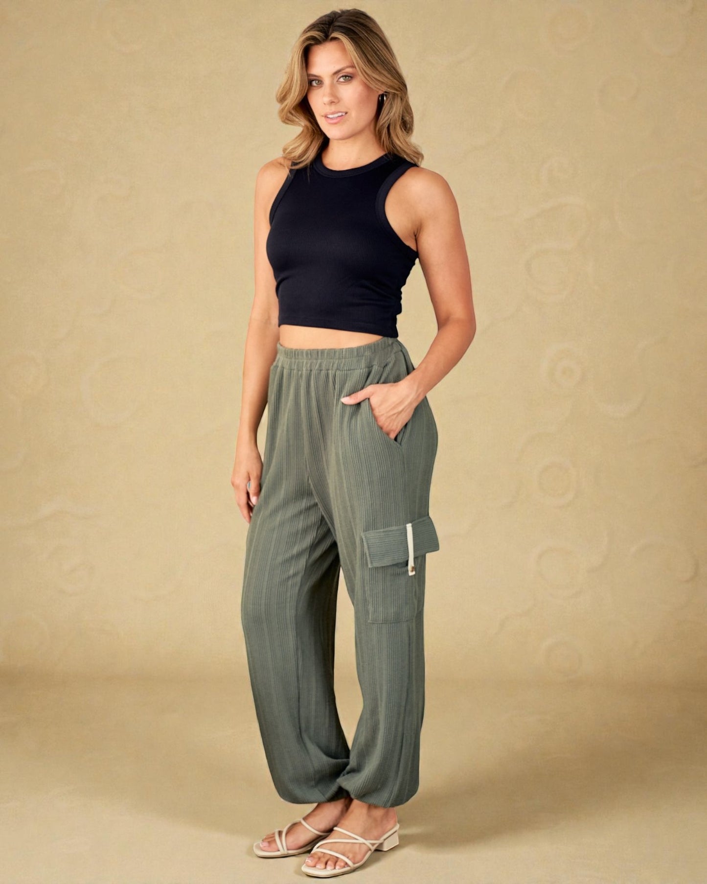 Woman wearing a black top and green cargo pants on a beige background