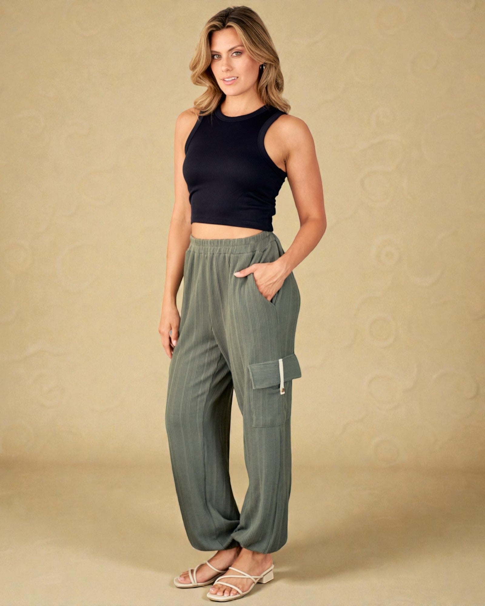 Woman wearing a black top and green cargo pants on a beige background