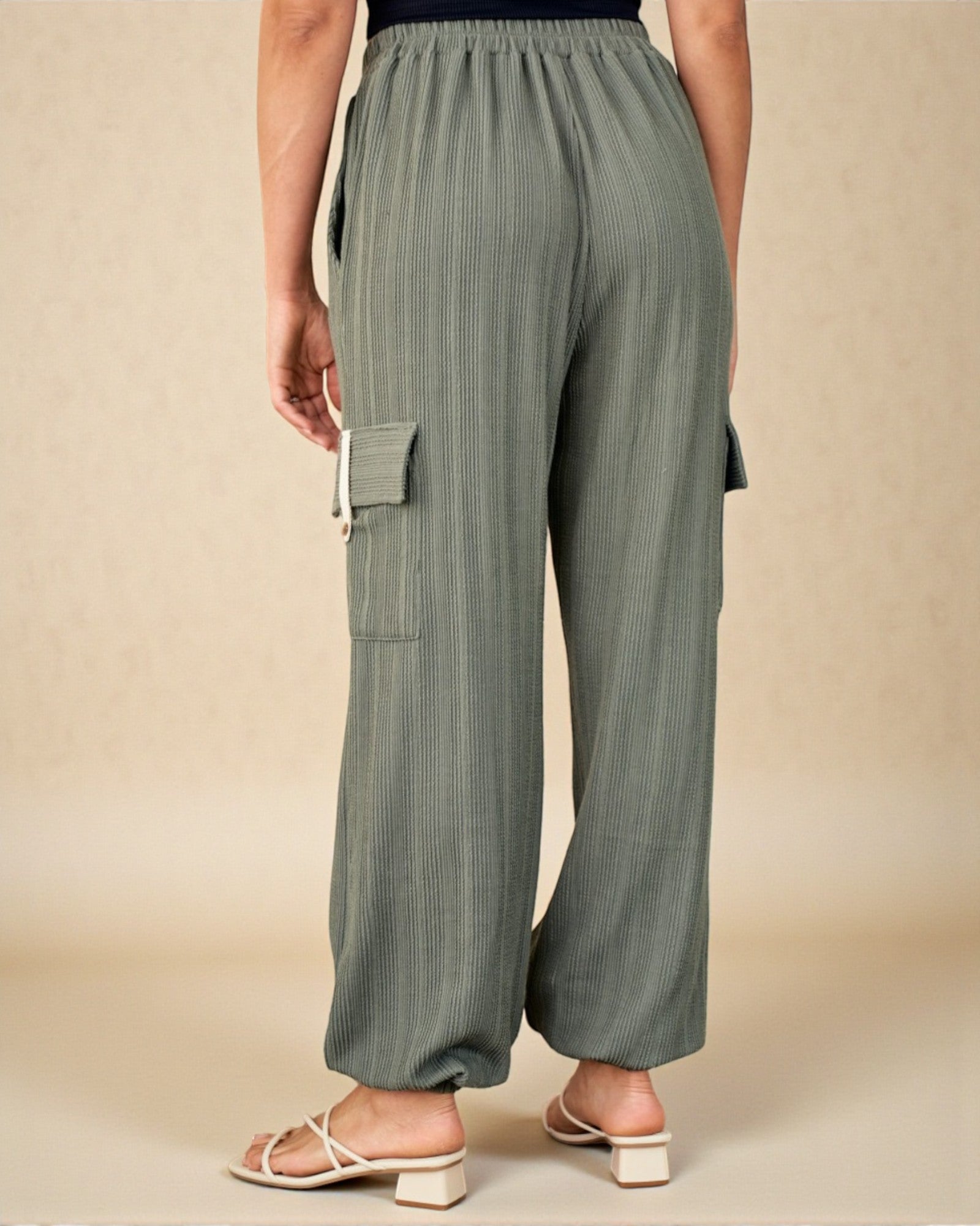 Person wearing green cargo pants on a beige background