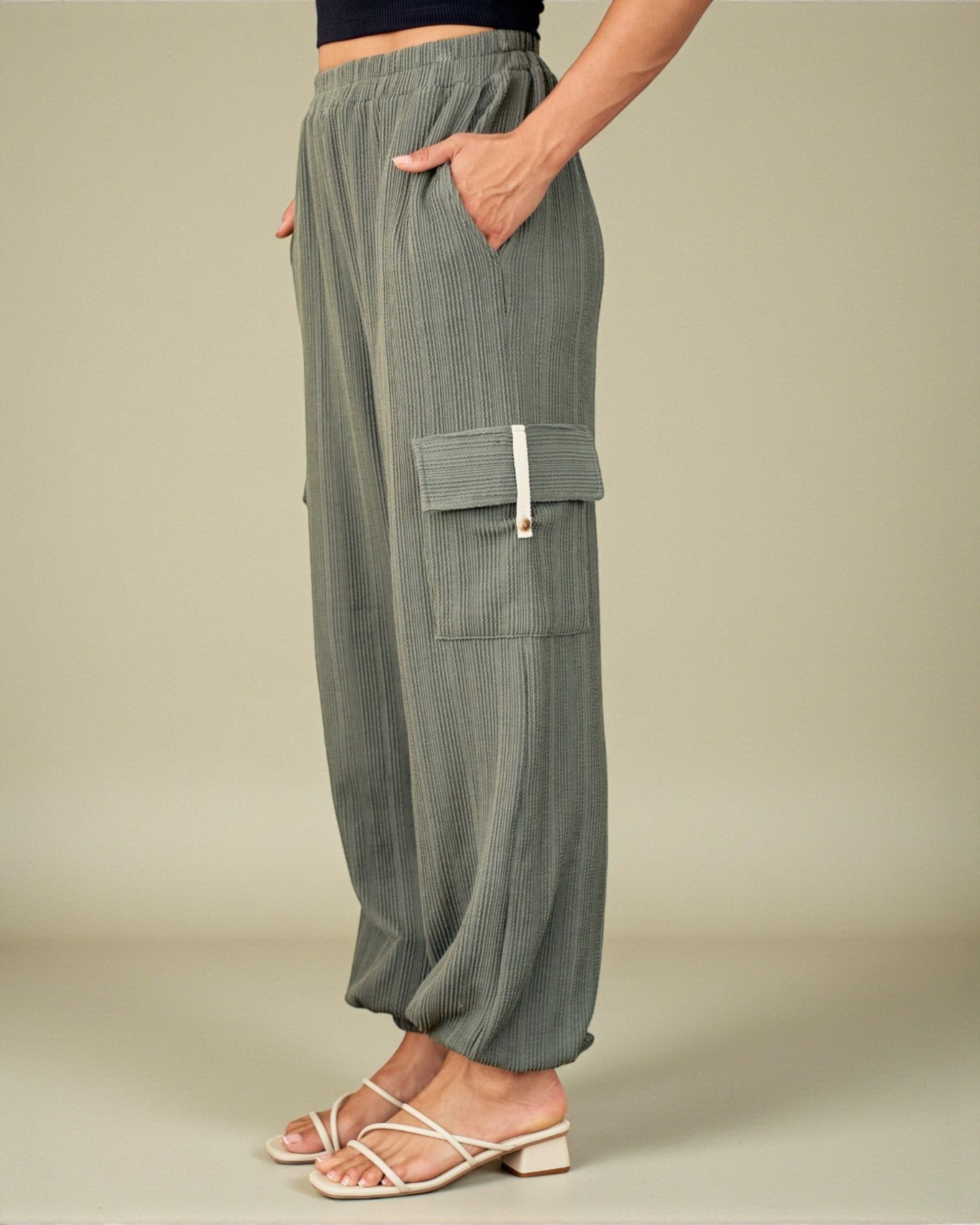 Person wearing green cargo pants on a beige background