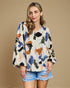 Woman wearing a floral blouse and denim shorts against a beige background