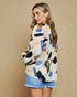 Woman wearing a colorful abstract patterned shirt against a beige background