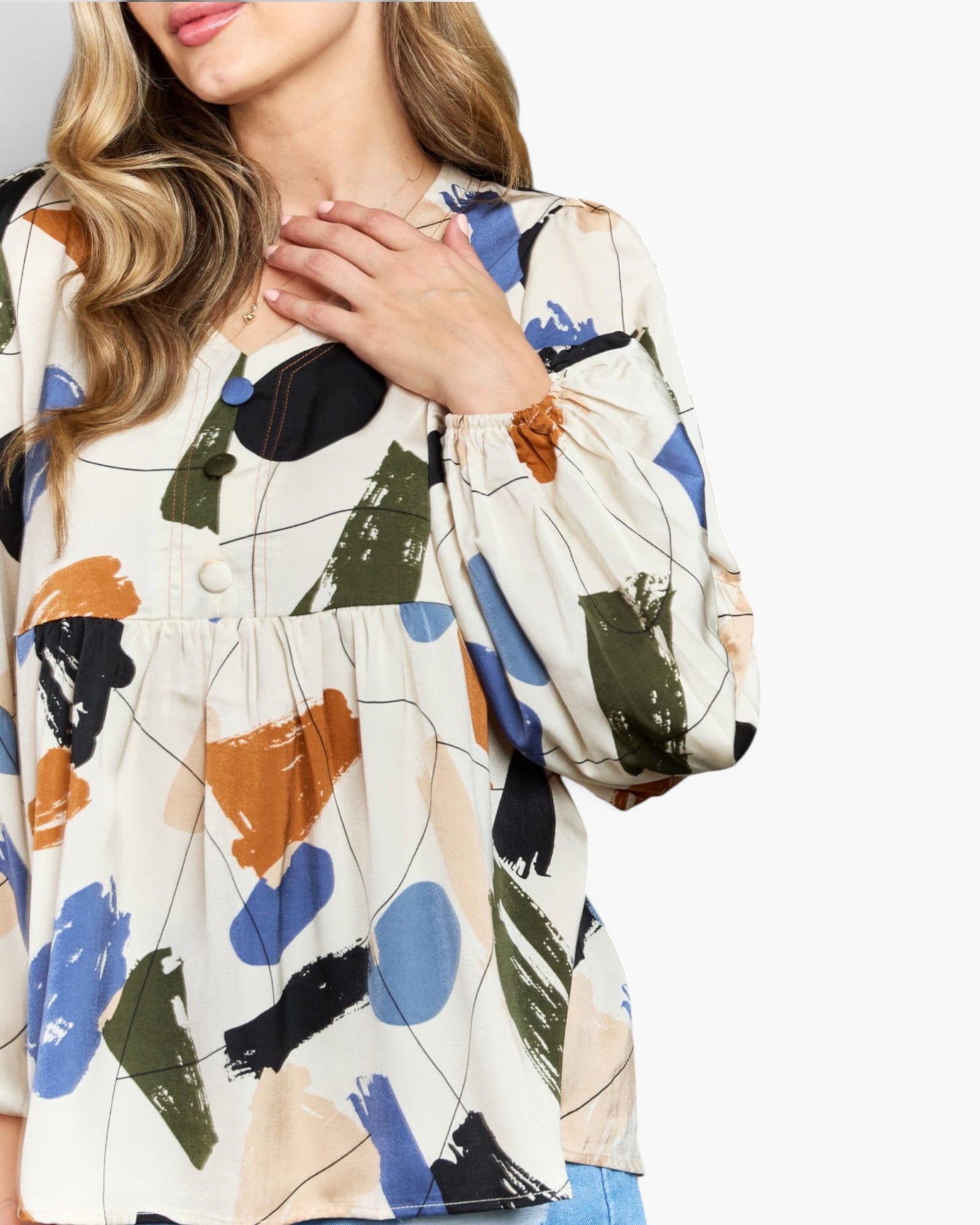 A woman wearing a long-sleeve blouse with an abstract brushstroke print in blue, green, orange, black, and beige on an off-white background.