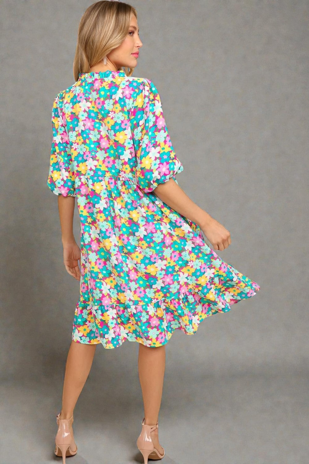 Woman wearing a colorful floral dress against a gray background