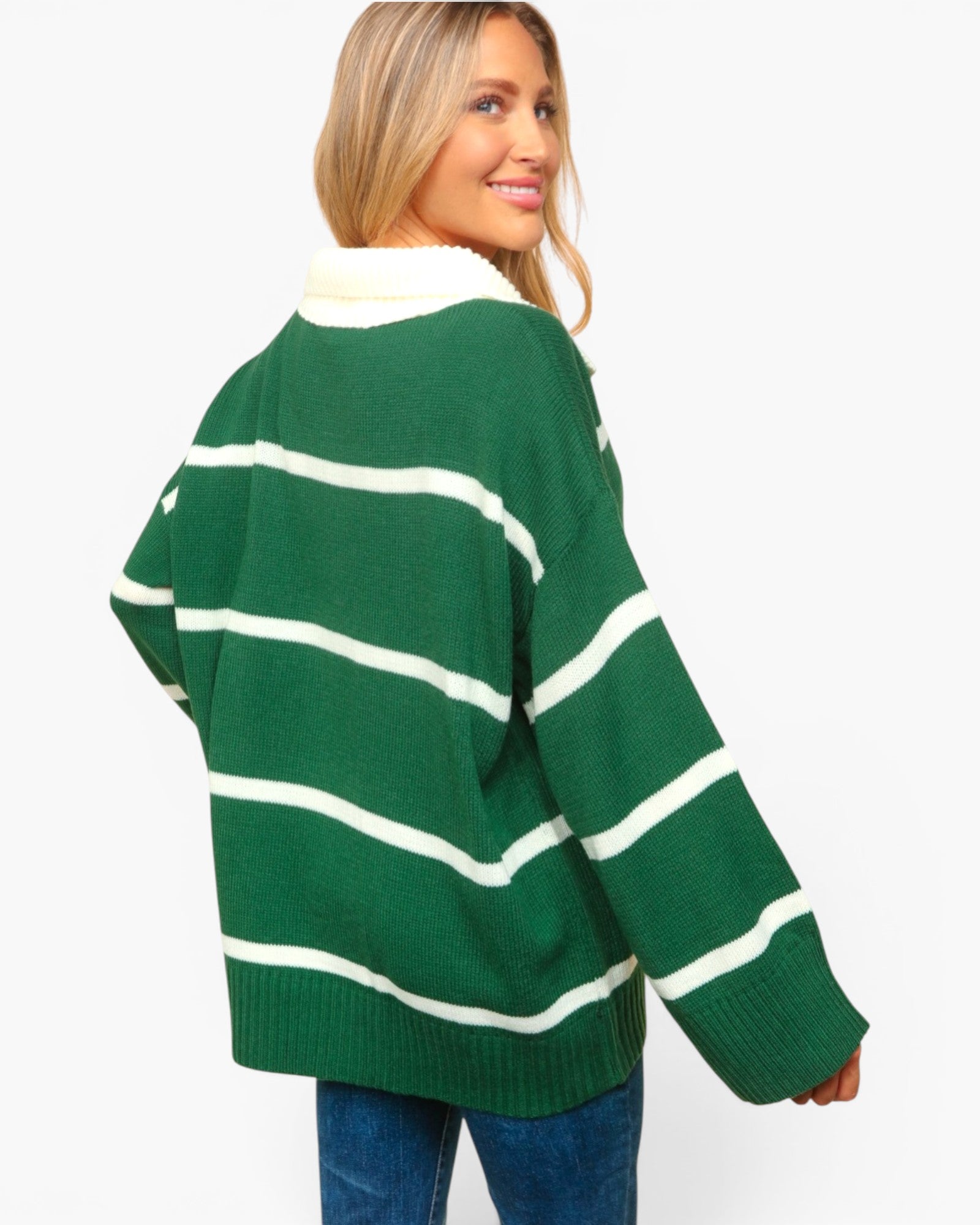 A woman wearing an oversized green knit sweater with horizontal white stripes, shown from the back against a plain light gray background.