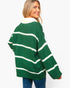 A woman wearing an oversized green knit sweater with horizontal white stripes, shown from the back against a plain light gray background.