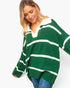 A woman wearing an oversized green and white striped knit sweater with a polo-style collar, paired with blue jeans, against a plain light background.
