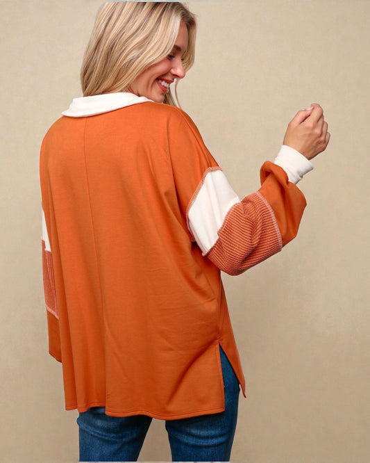 Woman wearing an orange sweater with white trim on a beige background