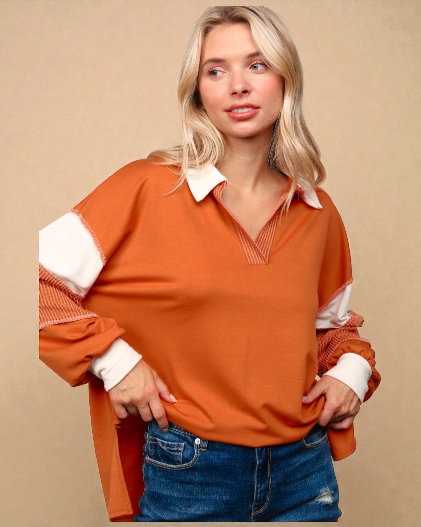 Woman wearing an orange and white long-sleeve shirt with a beige background