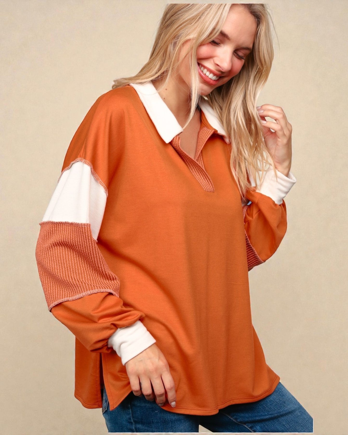 Woman wearing an orange and white long-sleeve shirt against a beige background