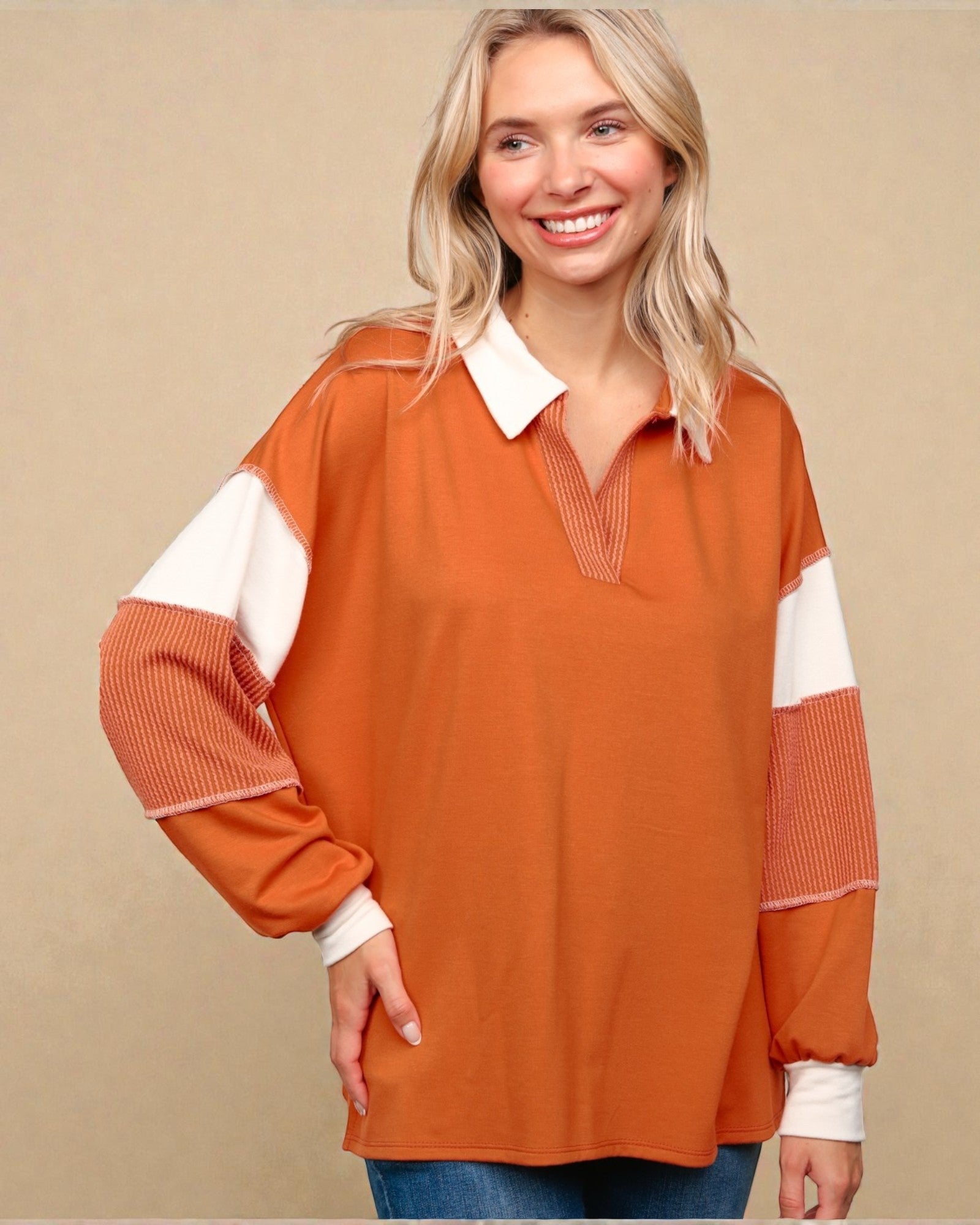 Woman wearing an orange and white long-sleeve top against a beige background