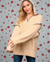 Woman wearing a beige sweater with black trim against a floral patterned background