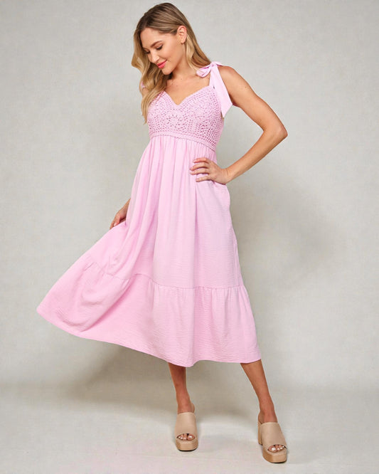 Woman wearing a pink dress with lace details on a plain background