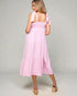 Woman wearing a pink dress with bow straps on a gray background