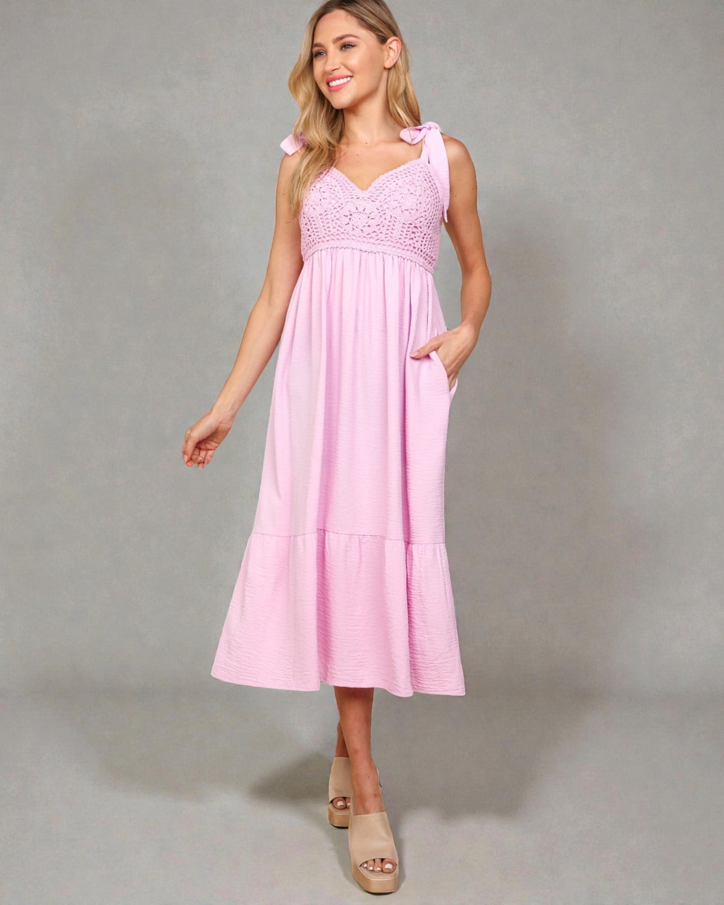 Woman wearing a pink dress with lace details on a gray background