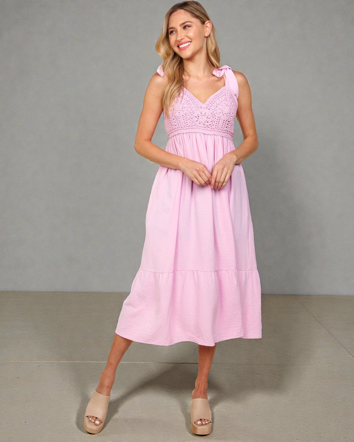 Woman wearing a pink dress against a gray background